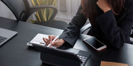 Mockup image blank white screen cell phone.women hand holding texting using mobile on desk at home office.の写真素材