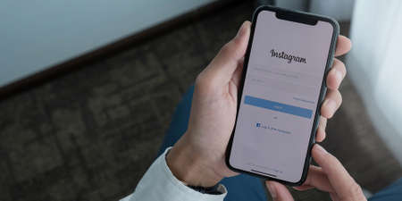 CHIANG MAI, THAILAND - AUG 26, 2020: A woman holds Apple iPhone X with Instagram application on the screen at cafe. Instagram is a photo-sharing app for smartphones.のeditorial素材