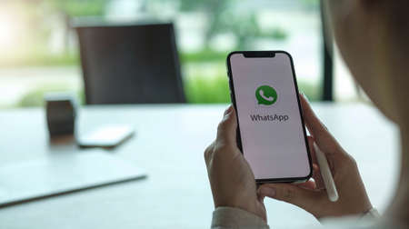 CHIANG MAI, THAILAND - APR 11, 2021 : Hands Holding Mobile Smart Phone Device With Whatsapp Company App Logo on Screen.のeditorial素材