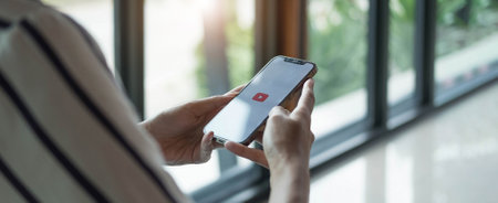 THAILAND - Jan 20, 2021 :Woman holding iPhone xs with video service YouTube on the screen. iPhone was created and developed by the Apple inc.のeditorial素材
