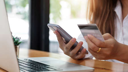 Online payment woman's hands holding smartphone and using credit card for online shopping. Cyber...