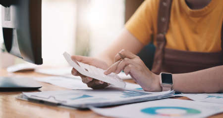 close up woman hand holding pen and pointing at financial paperwork with financial network diagram.