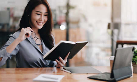 Portrait of a smiling Asian entrepreneur standing behind her cafe counter with open sign board