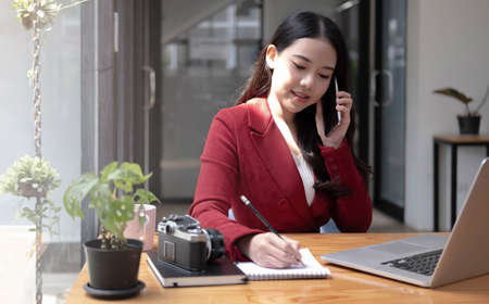 Portrait of success business asian woman enjoy success with laptop on work desk. Authentic shot joyful woman got jackpot, Surprised and celebrating her victory.の写真素材