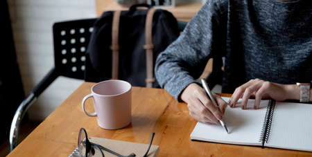 Cropped photo hand of woman writing making list taking notes in notepad working or learning online...