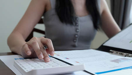 Close up woman using calculator and laptop for calaulating finance, tax, accounting, statistics and...