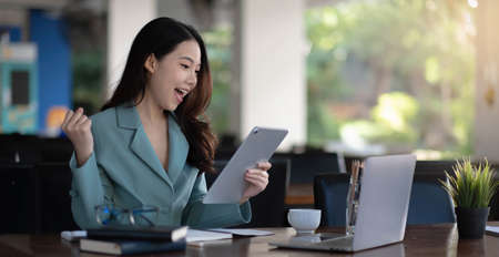 Businesswoman working with laptop computer and looking information on digital tablet.