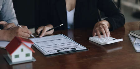 A real estate broker or insurance agent works with home models and home real estate sales contracts...