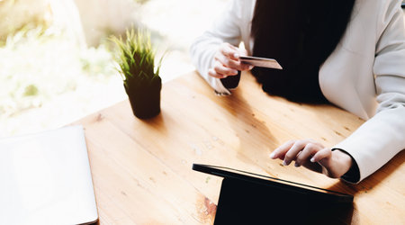 Online payment,woman's hands holding a credit card and using laptop computer for online shopping with vintage filter toneの写真素材