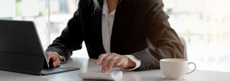 Business woman using calculator and writing make note with calculate. Woman working at office with...