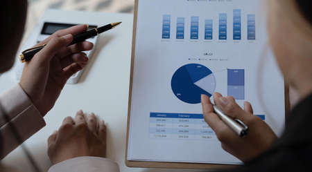 Business people meeting to find analytical ideas pointing to the graph at the office.