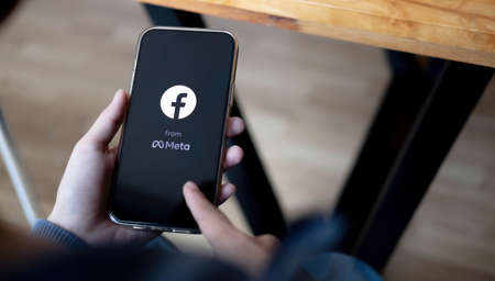 CHIANG MAI ,THAILAND MAR 18 2022 : Woman holding a iPhone Pro Mix with social Internet service Facebook on the screen.のeditorial素材