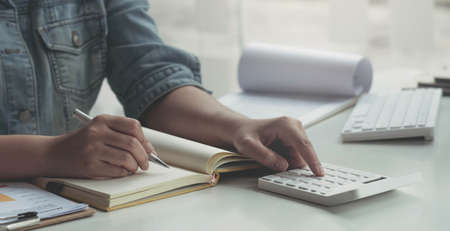 Close up asian woman working with financial data hand using calculator and writing make note with...