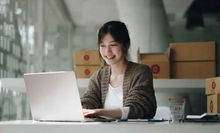 Startup small business entrepreneur SME, asian woman packing cloth in box. Portrait young Asian small business owner home office, online sell marketing delivery, SME e-commerce telemarketing conceptの写真素材