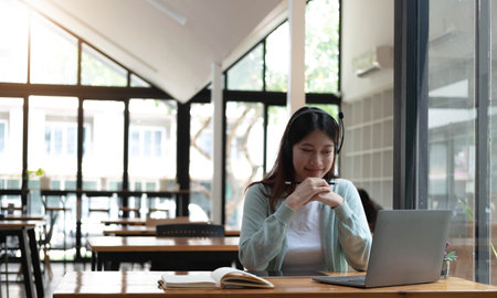 Happy young woman in headphones speaking looking at laptop making notes, girl student talking by...