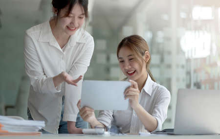 Two asian business woman work together to get the job done at the office.の写真素材