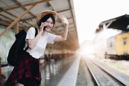 Young traveler woman looking for friend planning trip at train station. Summer and travel lifestyle conceptの写真素材