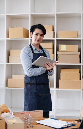 The seller Asian young man prepares the delivery box for the customer