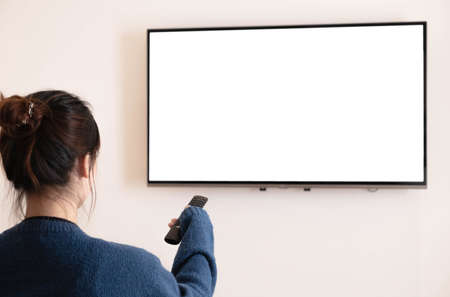 In front of a happy Asian woman looking at the camera. Behind the white TV on the sofa in the living room at home.の写真素材
