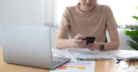 Asian businesswoman relax and enjoy playing mobile phone at office.