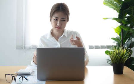 Asian businesswoman analyzes charts using laptop calculator at the office.の写真素材