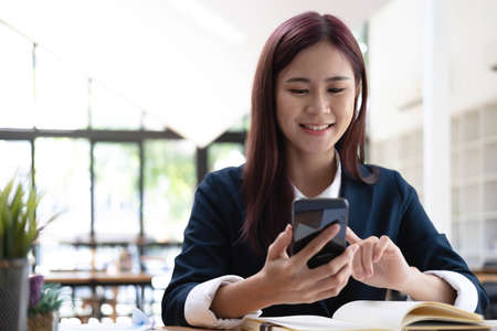 Asian woman talking on the phone and working on a laptop with a smiling face, Business Cell Phone...