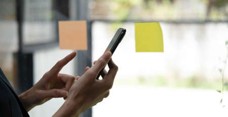 Close up of modern office desktop with blank white notebook screen, smartphone, coffee cup, supplies...