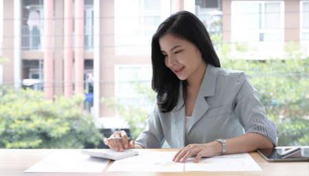 Asian business woman have the joy of talking on the phone, laptop and tablet on the office desk.