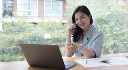 Asian business woman have the joy of talking on the phone, laptop and tablet on the office desk.
