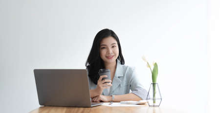 Beautiful Asian businesswoman analyzes charts using laptop calculator at the office.