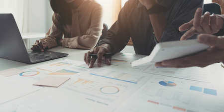 Business man working at office with digital tablet and laptop computer calculating financial report graph data documents on desk, close up, business analysis, work process conceptの写真素材