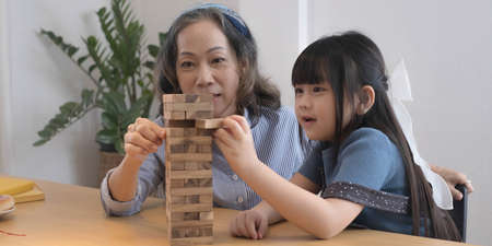 Little girl with her grandma playing game at homeの写真素材