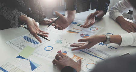 Group of business people meeting together Pointing to the graph assess business profits.
