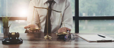 Male lawyer at table in office, focus on scales of justice