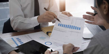 Group of business people meeting together pointing to the tablet assess business profits.