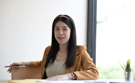 Portrait of smiling beautiful business asian woman working in modern office desk using tablet laptop...