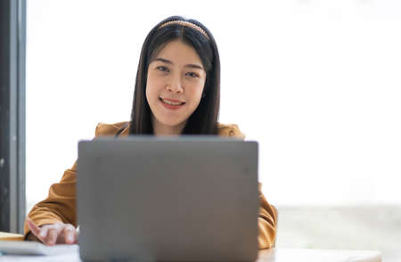 Portrait of smiling beautiful business asian woman working in modern office desk using tablet laptop computer, Business people employee freelance online marketing e-commerce telemarketing concept.の写真素材