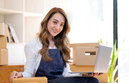 Portrait of Asian young woman SME working with a box at home the workplace.start-up small business...