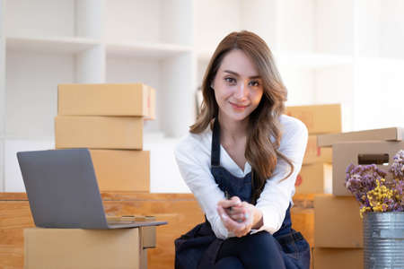 Portrait of Asian young woman SME working with a box at home the workplace.start-up small business...