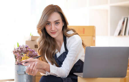 Portrait of Asian young woman SME working with a box at home the workplace.start-up small business...