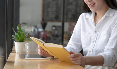 Beautiful young Asian woman or female college student relaxes sitting in the coffee shop and using portable tablet touchpad.の写真素材