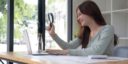 Business analyst using magnifying to review financial graphs, charts. Concept of Analyze return on...