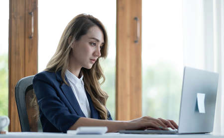 Charming Asian woman working at the office using a laptop Looking at the camera.の写真素材