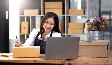 A female small business owner packing a customer's orders, writing a customer addressの写真素材