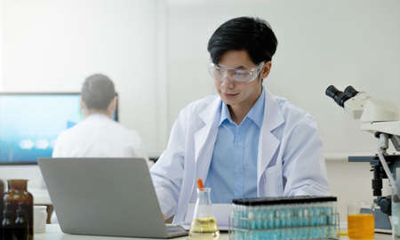 Medical Research Laboratory: Portrait of a Handsome Male Scientist Using Digital Tablet Computer, Analysing Liquid Biochemicals in a Laboratory Flask.の写真素材