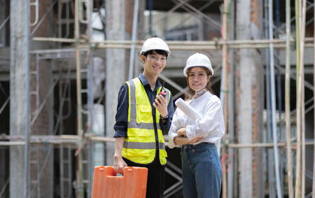 Two confident an engineers, architects or foremen standing with crossed arms pose in front of...
