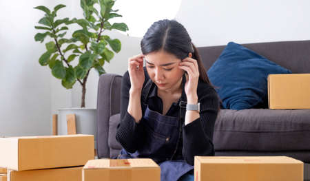 Young woman freelancer working and holding money with cardboard box  at home - SME business online...