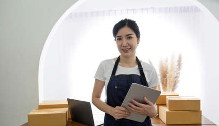 Startup SME small business entrepreneur of freelance Asian woman using a laptop with box Cheerful...