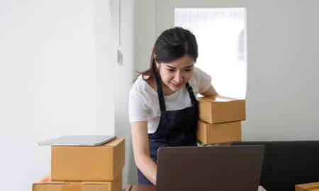 Startup SME small business entrepreneur of freelance Asian woman using a laptop with box Cheerful...