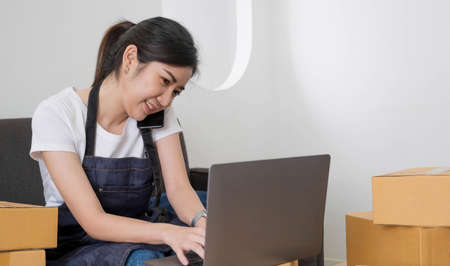 Startup SME small business entrepreneur of freelance Asian woman using a laptop with box Cheerful...